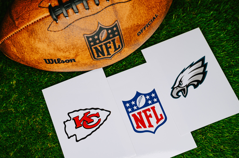 Ein Football und darunter die Logos von den Kansas City Chiefs und den Philadelphia Eagles