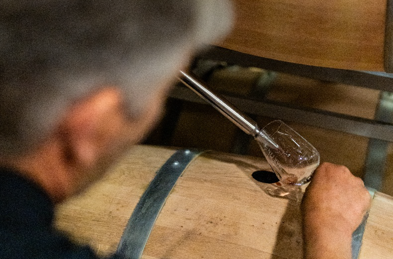 Achim Martin füllt mit einer Pipette Wein aus dem Fass in ein Glas zur Verkostung