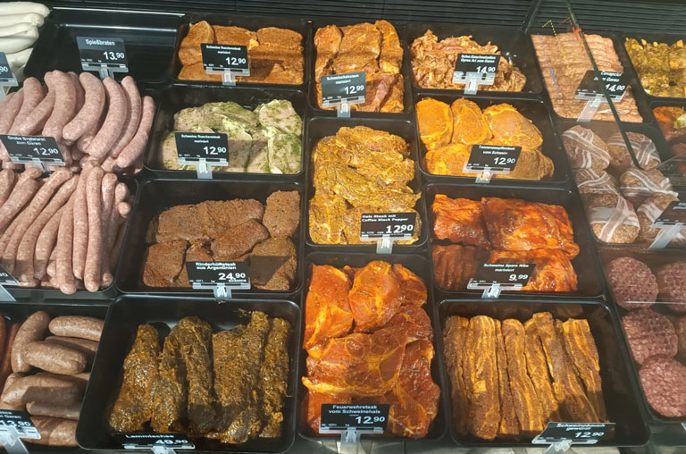 Verschieden marinierte Steaks vom Schwein in der Auslage der Bedientheke von EDEKA Deckenbach